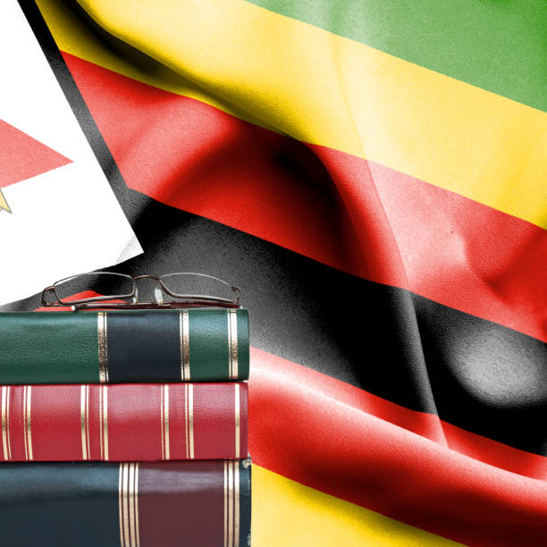 Education concept - Stack of books and reading glasses against National flag of Zimbabwe